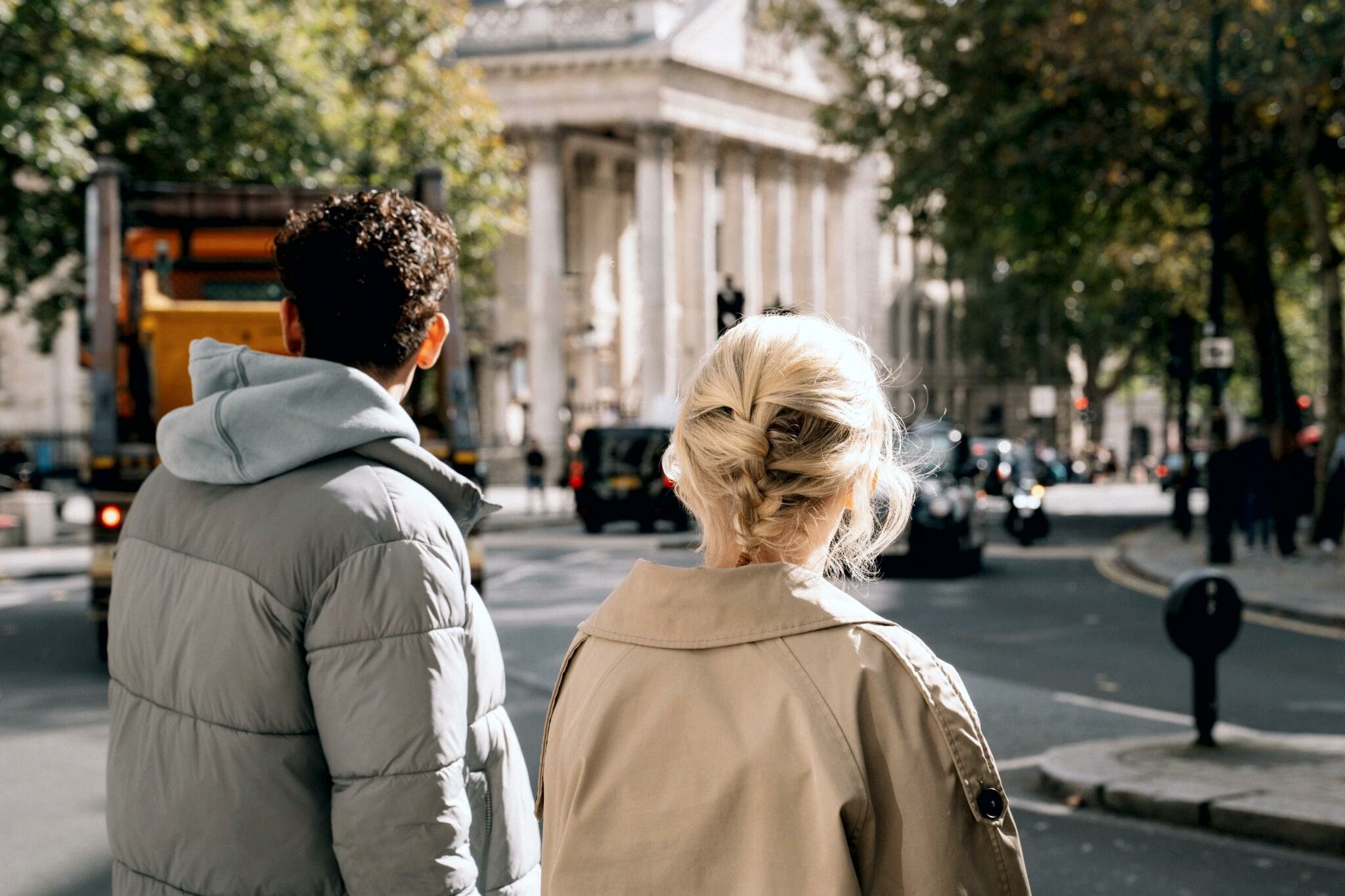 Two people walking through a bright city street