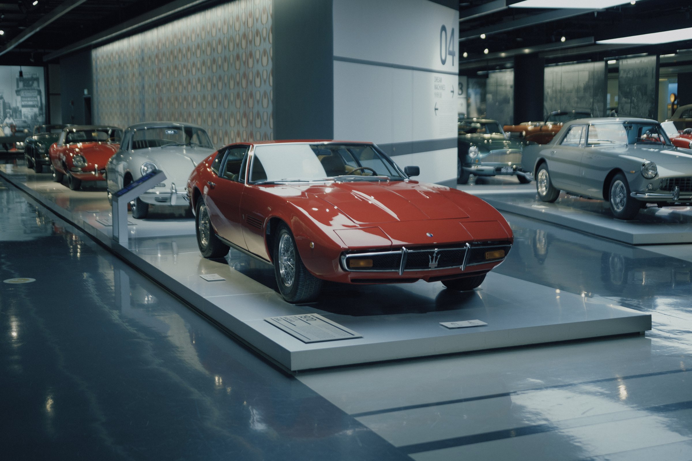 A red classic Maserati displayed in an indoor car museum, after