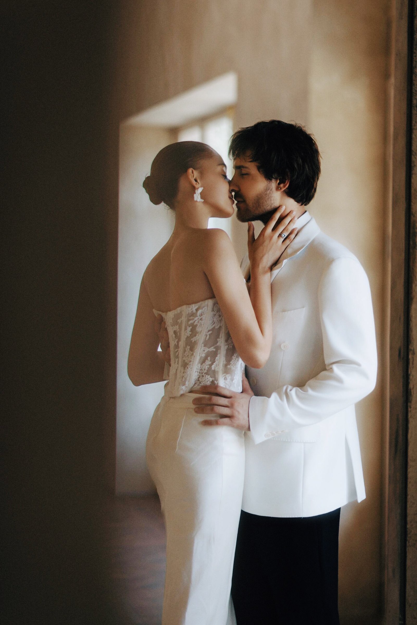 A wedding couple embracing in warm window light