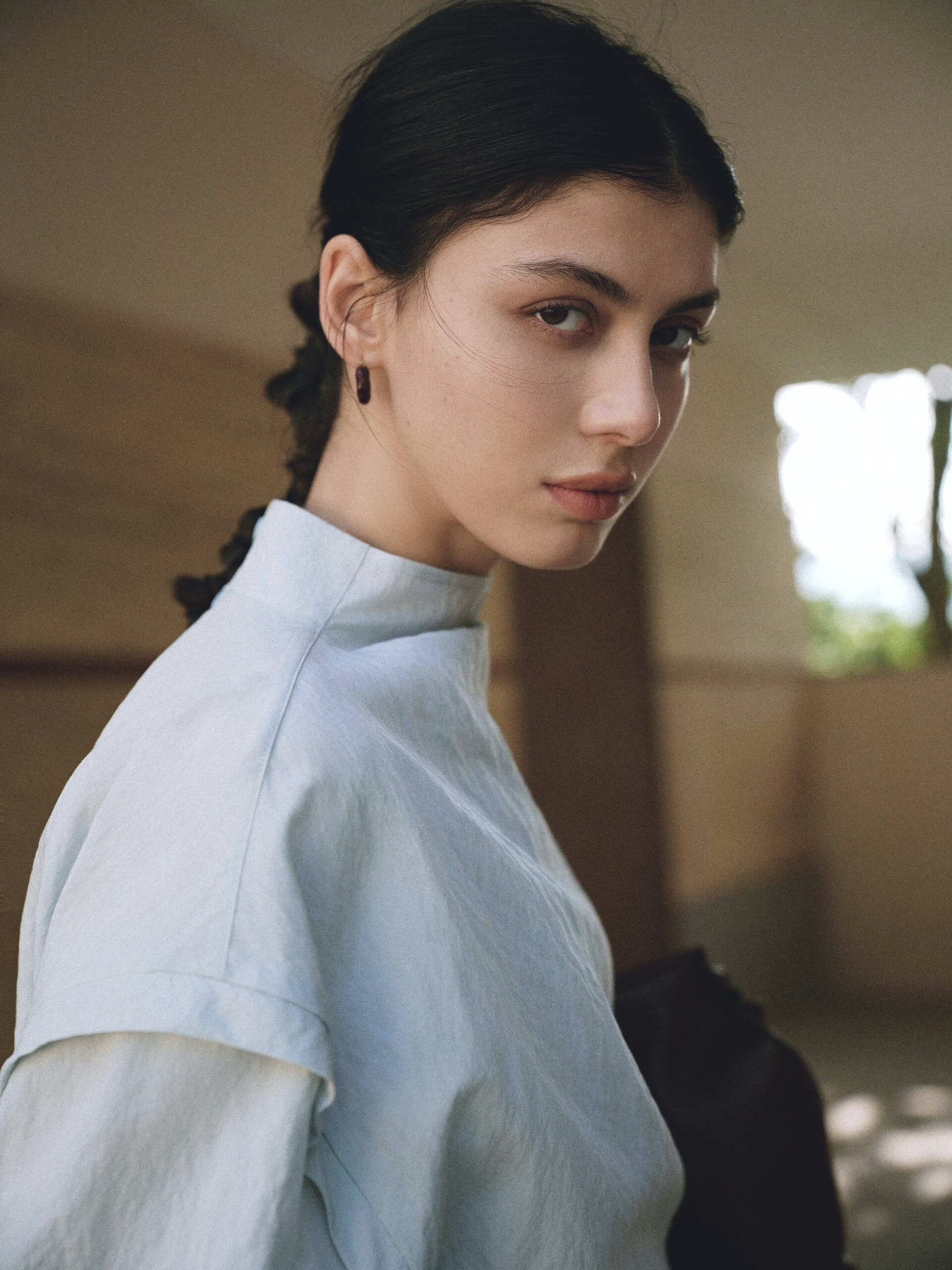 A close editorial portrait in pale blue clothing